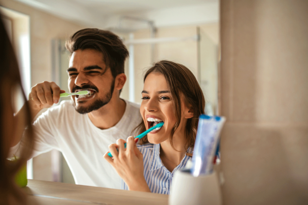 How-To-Prevent-Tooth-Decay a couple faces their mirror while brushing their teeth together and preventing tooth decay