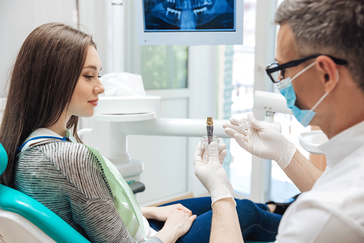 a dental patient sits in an exam chair and listens to her dentist explain the types of dental implants