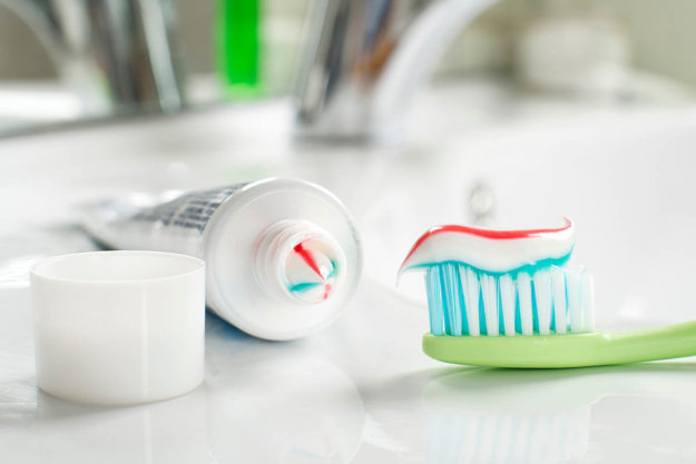 What Are the Benefits of Fluoride Toothpaste an opened fluoride toothpaste and tooth brush with toothpaste on it sits on bathroom counter ready to be used after dentist explains benefits of fluoride toothpaste