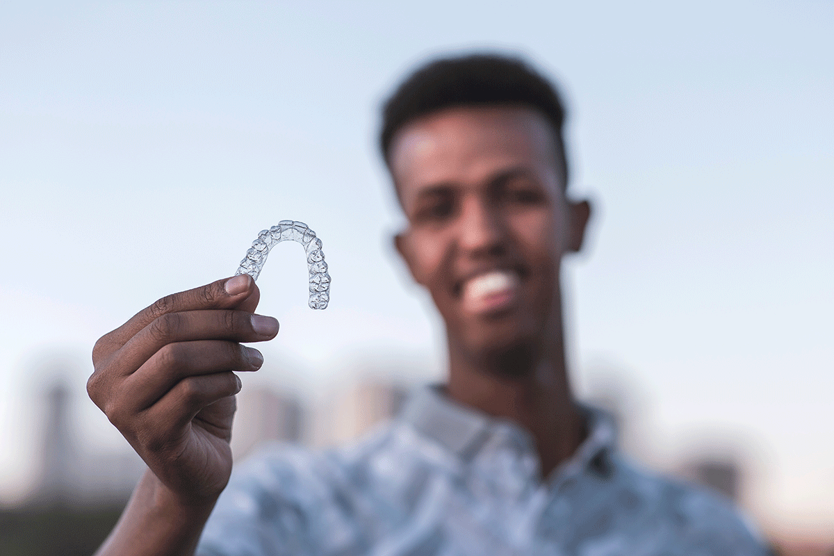 a young man holds up his clear aligner and starts to talk about the benefits of invisalign