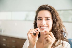 a woman holds her aligner tray as she considers clearcorrect services