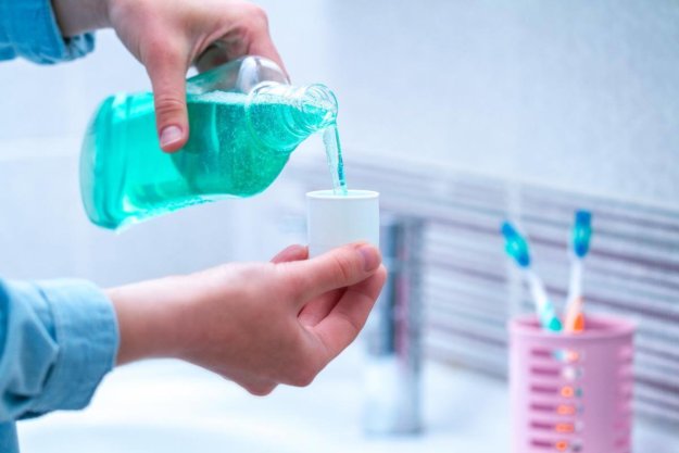a person pouring fluoride mouthwash into a cup and understanding the benefits of fluoride mouthwash