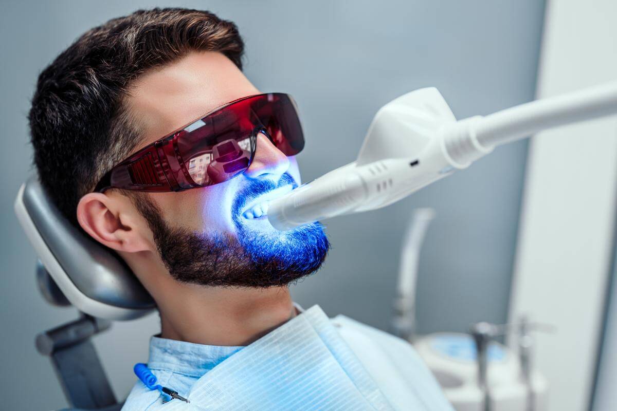 a man sits in dental exam chair undergoing teeth whitening services to fix discoloration in his teeth