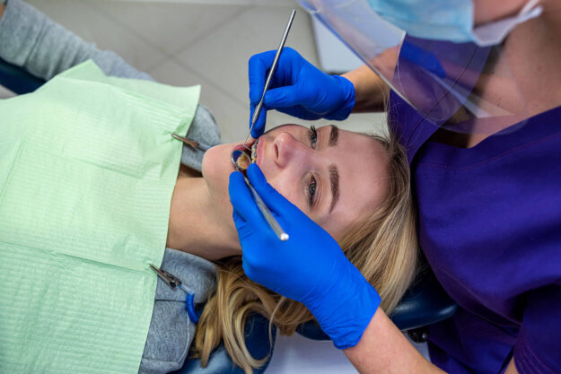 a female patient sits in dental chair receiving a root canal from dental professional and asks can I exercise after root canal