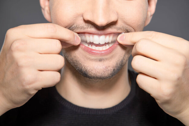Are Whitening Strips Bad for Your Teeth a man puts on a whitening strip as he asks himself are white strips bad for your teeth