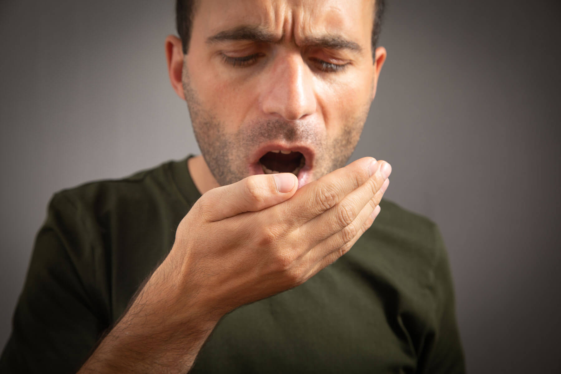 How to Get Halitosis Cured Permanently man blows into his hand wondering if halitosis can be cured permanently