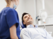 man smiles while laying back in dental exam chair while asking how long does tooth extraction take to heal to the dental professional next to him