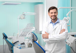 a dentist stands in his office near exam chairs and explains his services for dental bridges