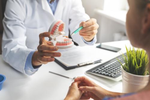 a dentists holds up a model of a mouth and explains to a patient about receiving a root canal temporary filling
