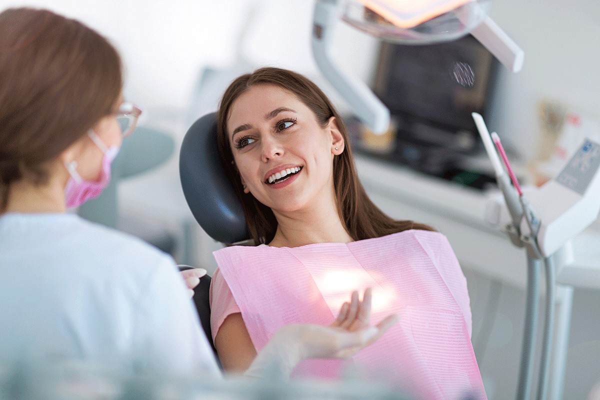 How-Long-Does-Teeth-Whitening-Last woman lays back in dental exam chair and asks dental professional how long does teeth whitening last