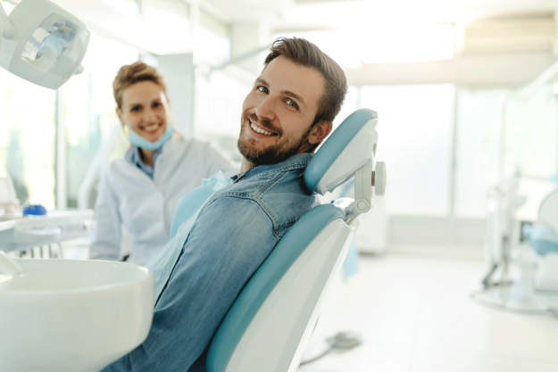 a dentist and a patient sit in an exam room and smile after the dentist answered the patients question about when to consider teeth whitening