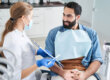 a man sits in dental exam chair and talks to hygienist about his fear of dentists