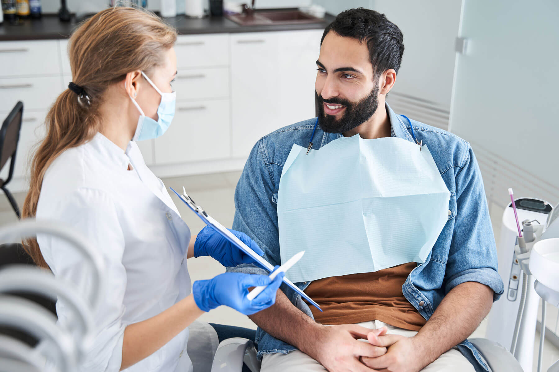 a man sits in dental exam chair and talks to hygienist about his fear of dentists