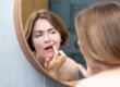 woman looks in the mirror touching her tetracycline stained teeth