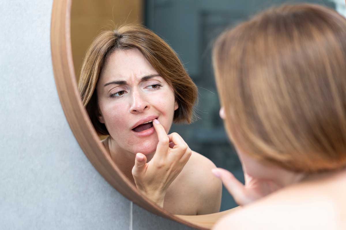 woman looks in the mirror touching her tetracycline stained teeth