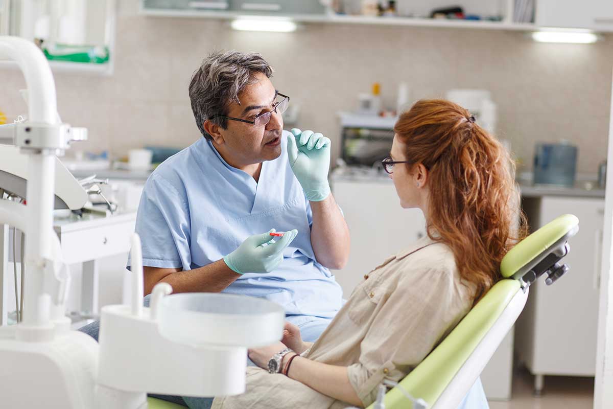 doctor sits and talks to a patient in an exam chair about composite bonding and its cost