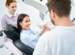 two dental professionals talk to a patient in an exam chair about a single tooth implant