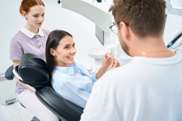 two dental professionals talk to a patient in an exam chair about a single tooth implant