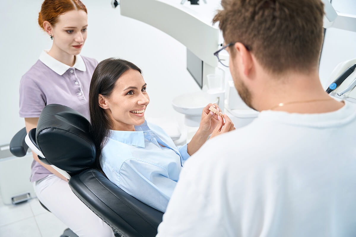 Single Tooth Implant- What You Should Know two dental professionals talk to a patient in an exam chair about a single tooth implant