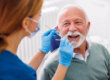 older adult man smiles while dentist is about to tell him the importance of regular dental check-ups