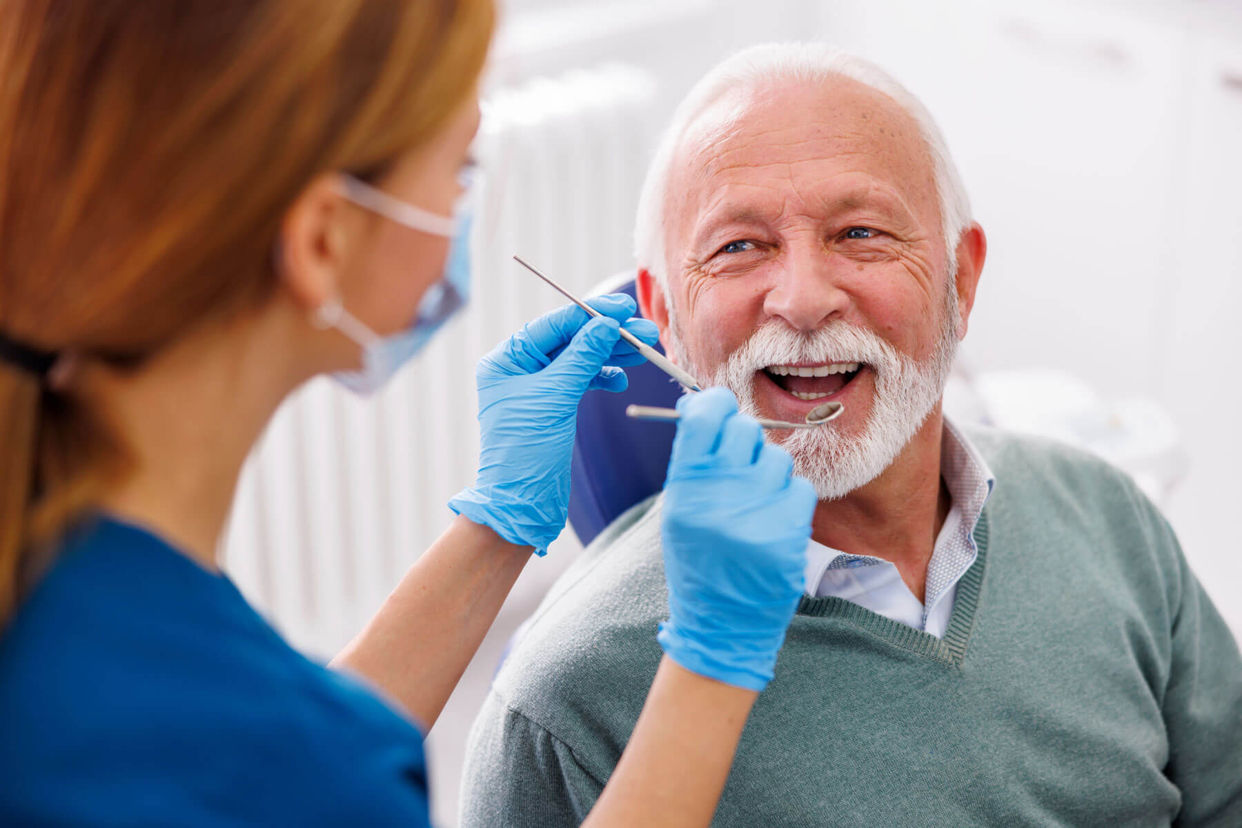 The Importance of Regular Dental Check-Ups older adult man smiles while dentist is about to tell him the importance of regular dental check-ups